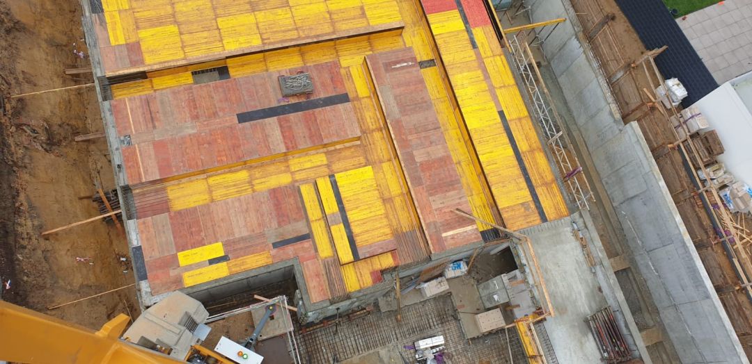 Blick von oben auf gestellte Wandschalung mit gelben Rahmenelementen und roten Schalhäuten